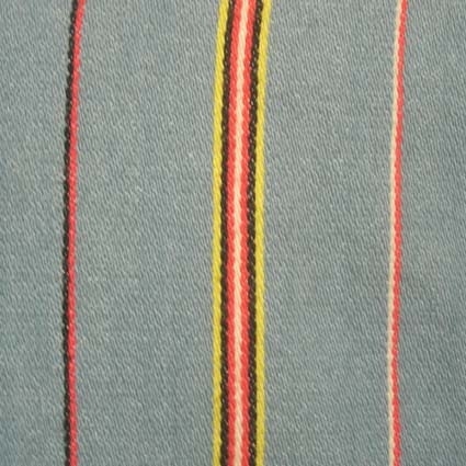 Tröja, kallad "Tvärarmatröja", ytterplagg till Lövångersdräkten. Handvävt ljusblått halvylle i oliksidig korskypert med inslagseffekt. Ränder i rött, gult, svart och vitt. Tröjan är midjekort med söm mitt bak och öppning fram. Ryggstycket, ärmen och övre delen av framstycket är skuret i en del. Framstyckets nedre del går långt bak på ryggen, sidsömmarna ca 50 mm från sömmen mitt bak i nederkant. Öppningen fram knäpps ca 90 mm omlott med sju hyskor och hakar. Helfodrad med grovt linne. Handsydd.Orginalet till tröjan från Lövånger finns på Nordiska museet. Tröjan stod som förebild för livstycket till Västerbottensdräkten.