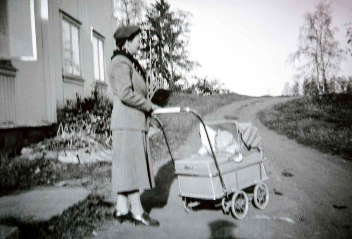 Ingrid Gjestvang triller sin datter Ellen på tur i barnevogn. Vestre Ottestad, Stange.