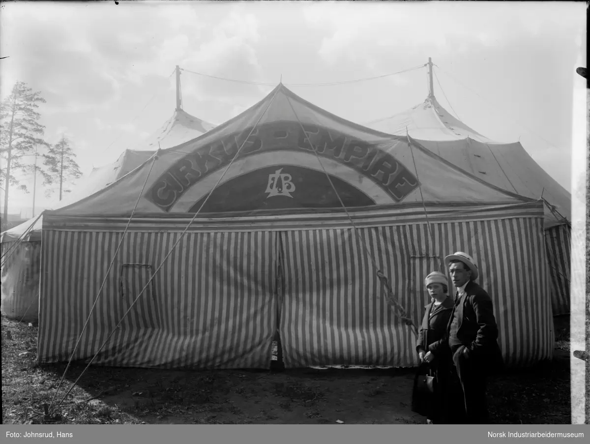 Inngangspartiet av sirkusteltet til Cirkus-Empire. En mann og en kvinne står på høyresiden av bildet