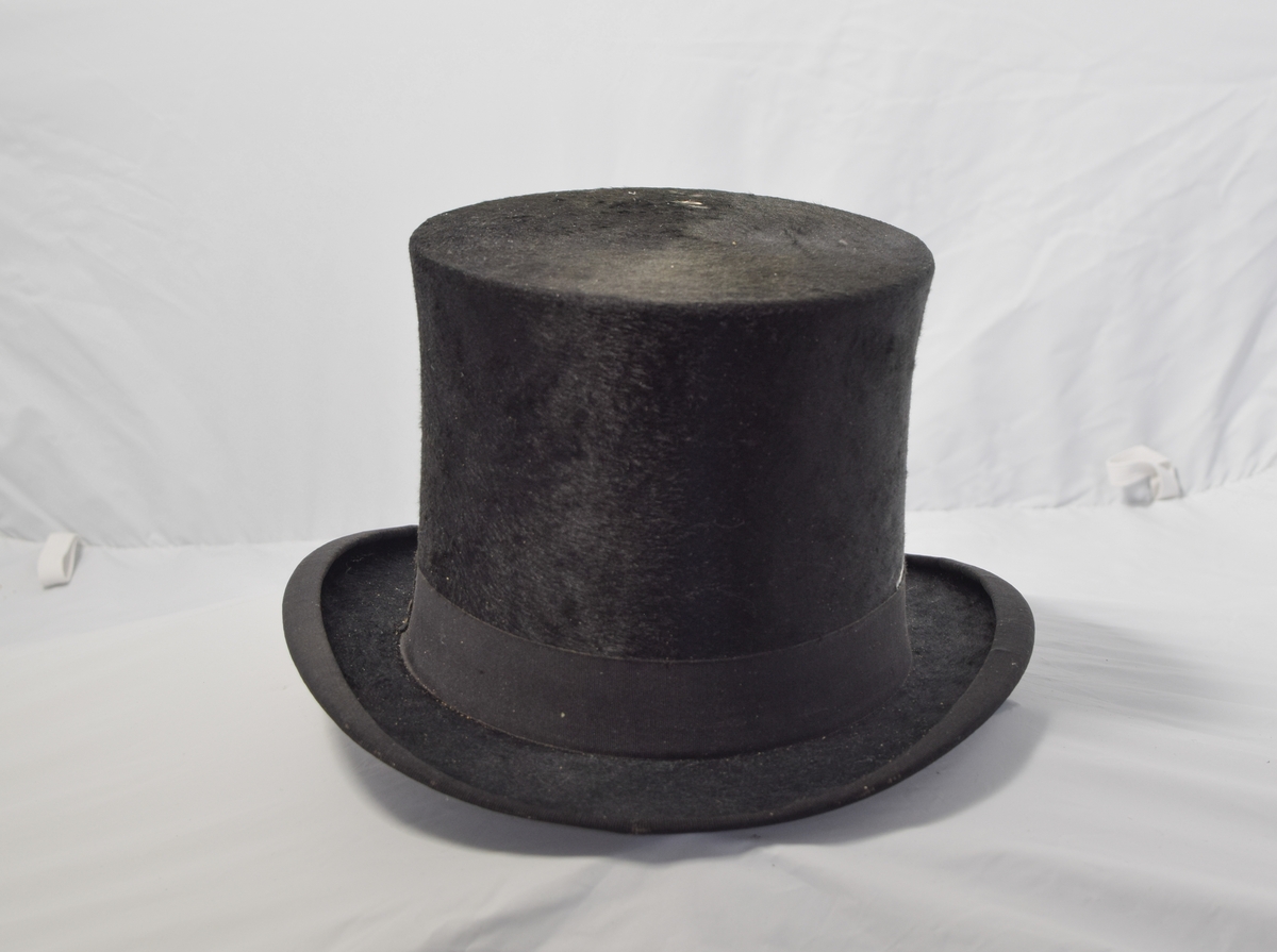 Svart og lav flosshatt. Hatten har motivstempel på innsiden av hatten.