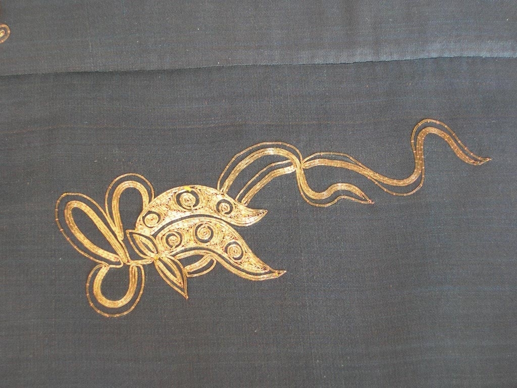 Kvnnojacka, troligen använd av mandarinhustru, en ämbetsdräkt. Bärs vanligen tillsammans med byxor eller veckad kjol.
Blåsvart sidentyg, tuskaft. Rak ärm.
Fram- och bakstycke dekorerade med guldbroderi, läggsöm sydd med tvärstygn, roströd silketråd. Guldtråden är gjord av pappersguld virad runt en silkekärna. Vissa mönsterformer har en klassisk symbolik, t.ex. ärtskidan för fruktbarhet, andra former är av mer dekorativ art.
Dekorativa band runt framkant, nederkant och sprund. Ytterst ett kantband i blått siden, därefter ett band, silkebroderi, 3,5 cm,  blommor och cirklar i vitt och olika blå nyanser samt guldbroderi, innerst ett mönstervävt band, 2 cm brett. I halsringningen ytterst ett kantband i blått siden, därefter ett band, silkebroderi, likadant som på kantningen runt nederkanten, därefter en snedremsa i siden , ca. 1 cm bred, och innerst ett mönstervävt bant, 1.5 cm brett.
På ärmen snedremsa i blått siden, ca. 1,5 cm bred därefter band i silkebroderi likadant som runt nederkant och halsringning. Ytterst ett tyg, 12 cm brett, dekorerat med mönstervävt band i blått och guldfärg. Tyget är broderat? med tråd i liknande färg som tuskaftsbottnen. Åtdragen plattsöm som bildar mönster tillsammans med den något grövre tråden. Symboliska mönsterformer, de 8 taoistiska symbolerna,  bl.a. flöjt, solfjäder och lotusblomma mellan dessa dekorativa mönster, S-formade. Ärmens baksida och ca. 1/4 av framsidan täckt med guldbroderi, läggsöm sydd med tvärstygn, guldfärgad tråd, och detaljer i silkebroderi, svart, vitt och lila, platt- knut och klyvsöm. Mönstret föreställer bl.a. vattenströmmar, vågskvalp och en drake som stiger upp ur vattnet. Draken har 4 klor och symboliserar den näst högsta rangen, den högsta har 5 klor och det är kejsarens symbol. Draken är en positivt laddad symbol, en manlig symbol.
Jackan knäpps med tre klotformade mässingknappar och öglor gjorda av svarta, runda band.
Foder: ljusblått siden.
En märkning på  höger framstyckes insida i halsringen, kinesiska tecken skrivet på tyget och på en vit klisterlapp.
Uppgifter om detta plagg, dess  historia och symbolik är inhämtade från Marianne Erikson, tidgare intendent vid Röhsska museet.

Funktion: Kina,