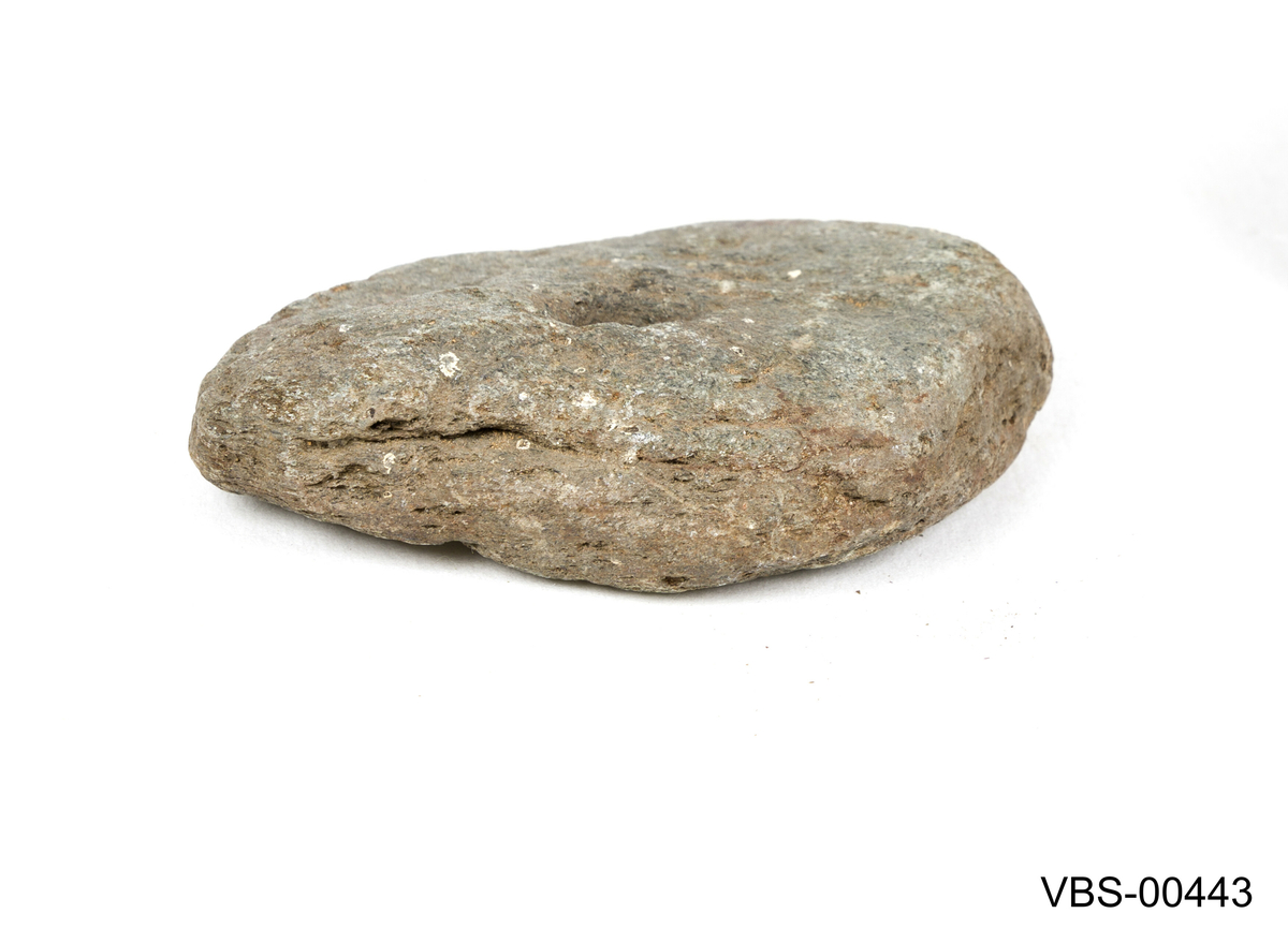 Flat stein, litt trekantet og avrunded i formen, med hull på den ene siden.