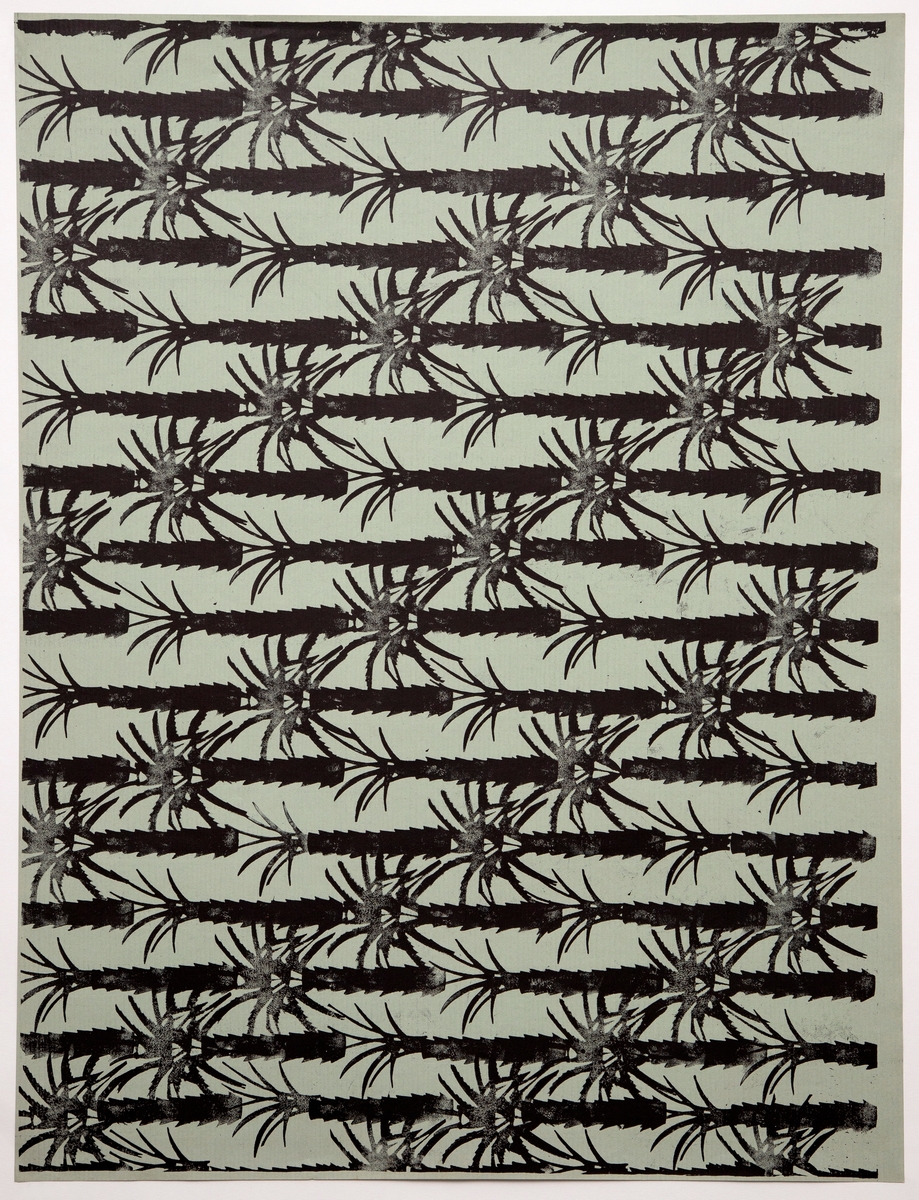 Rektangulært dekorativt papir med mønsteret "Palmerne". Forsiden er dekorert med et repeterende mønster av stiliserte palmetrær i sort silhuett på grågrønn bunn.