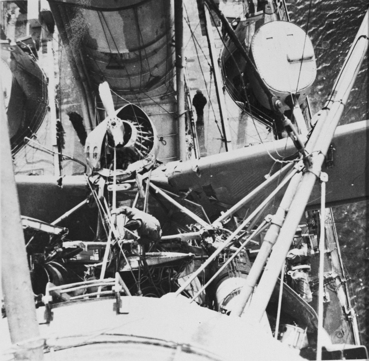 Flygplan S 5C har kolliderat med pansarfartyget Gustav V under mörkläggningsövning i Karlskrona den 10 mars 1939. Vy ovanifrån. En soldat står vid flygplanets nos.