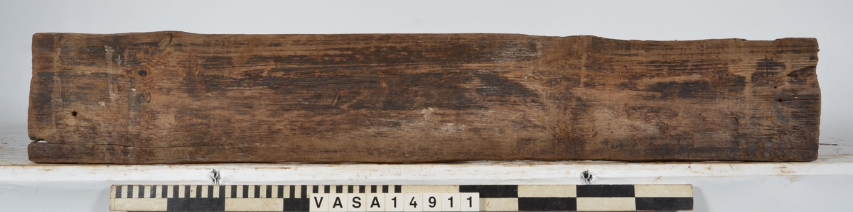 Bräda som tillhör alpumpkistan i hålskeppet. Stor längsgående spricka vilken separerar detta föremål från 14734. En del skador på kanterna.