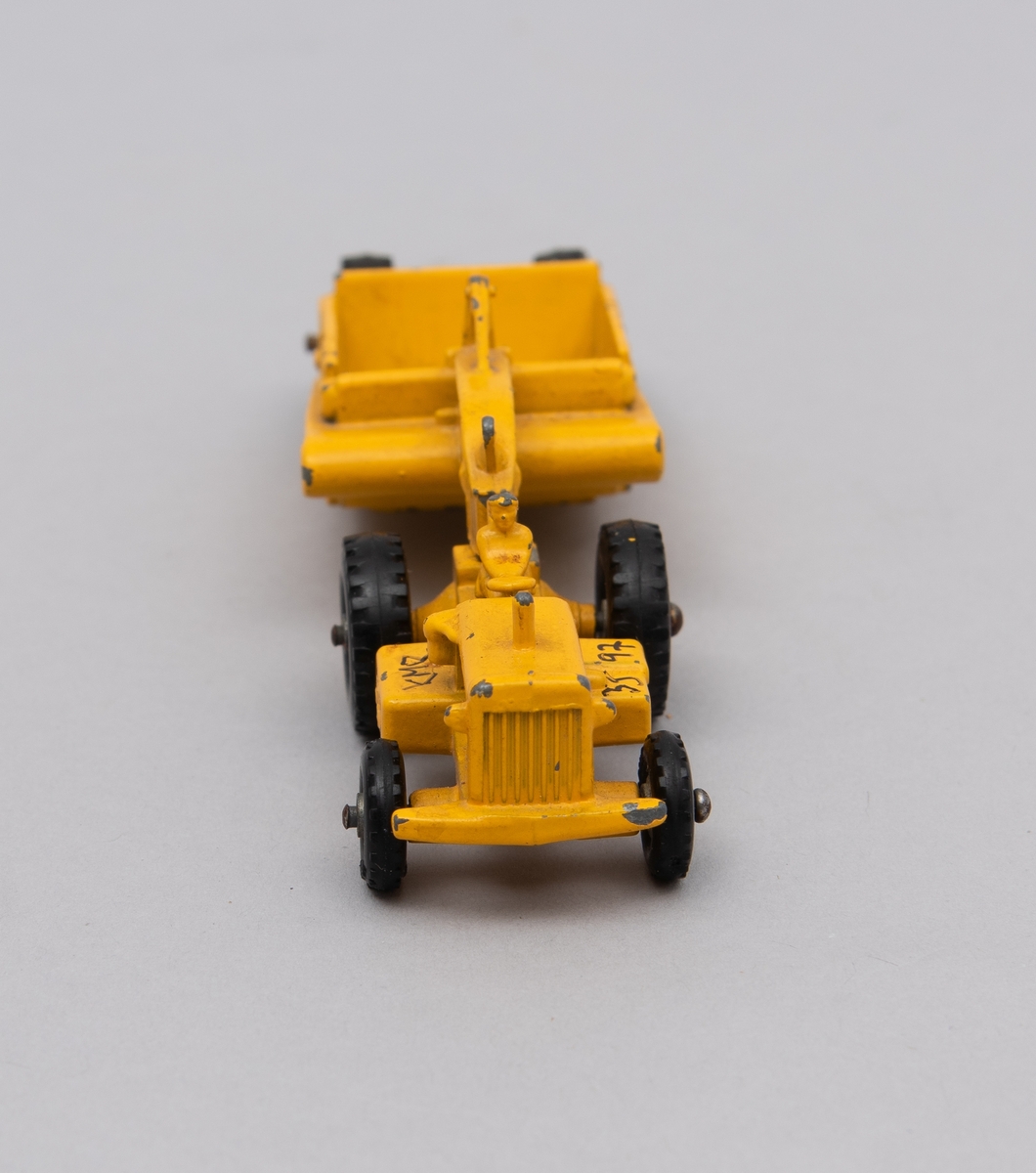 Gitt av Lisbeth Andreassen Chumak.
Traktor med henger. Begge i metall. De er gule og på traktoren sitter en mann/bonde.