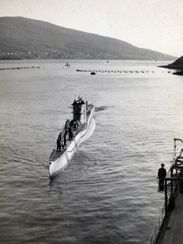 Tysk ubåt U-251 med kurs mot "Tanga" -stabskipet til Admiral Nordmer. "Tanga" her fortøyd mot restene av malmkai 3 på LKAB, lå i Narvik i tiden mai-oktober 1942. Ubåtnett/nettspering ses i bakgrunnen.