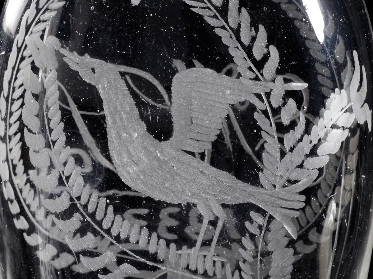 Plunta. 
Graverat växtmotiv på ena sidan samt monogram "E.M. Json 1833" inom bladkrans. En fågel på den andra sidan.
Ofärgat klarglas.
Ovan angivna mått avser flaskans längd och bredd samt mynningsdiameter.
Inskrivet i huvudkatalogen 1935.
Funktion: Brännvinsplunta
