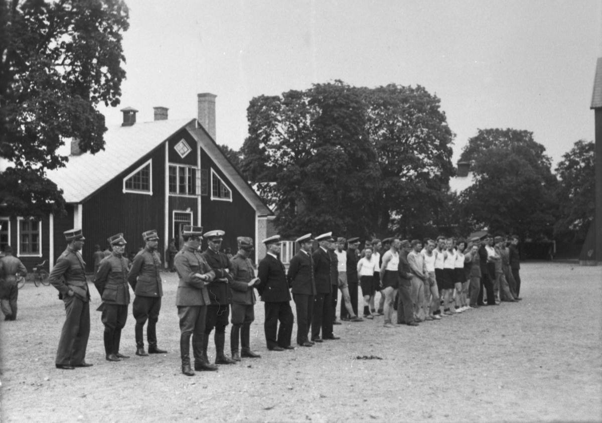 Officerare och manskap uppställda på flottiljområdet på Malmen, ca 1925-1930. Klädda i uniform respektive idrottskläder.