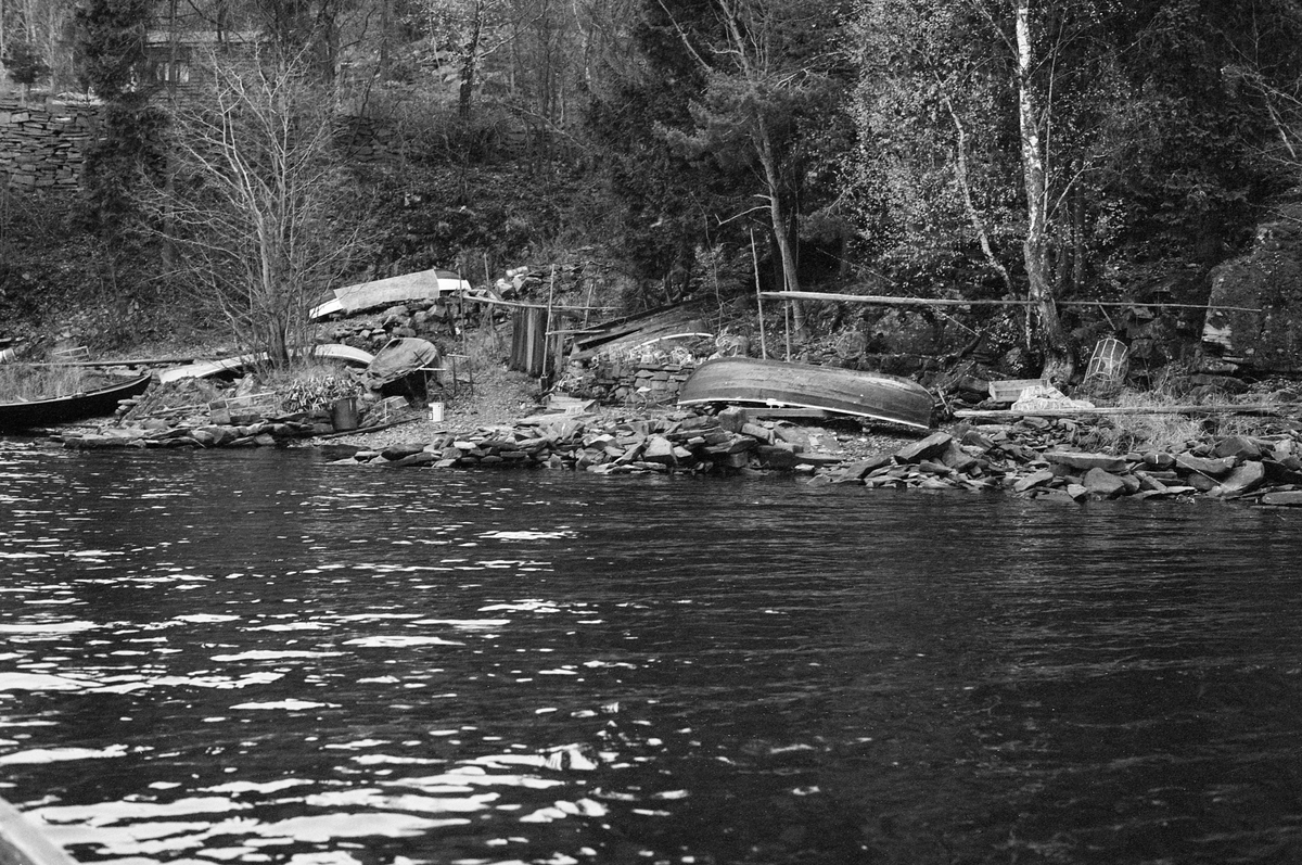 Båtstøa til yrkesfisker Paul Stensæter (1900-1982) ved Steinsfjorden, ei sidegrein til Tyrifjorden på Ringerike i Buskerud. Fotografiet er tatt fra vannet, inn mot strandsona, der det lå fire klinkbygde trebåter. En av dem var bare trukket så vidt opp på land. Den var øyensynlig stadig i bruk. De tre andre lå lengre oppe på land, og to av dem var snudd, slik at kjølsida vendte opp. Det er nærliggende å tenke seg at disse ikke var i daglig bruk, og at de lå slik for å unnga at de samlet vann, som i verste fall kunne påføre dem frostskader. Bildet ble tatt seint i oktober 1973, så det var absolutt fare for frost.  I tillegg til båtene ser vi også et stativ Paul Stensæter hadde lagd seg for å kunne tørke fiskegarn.