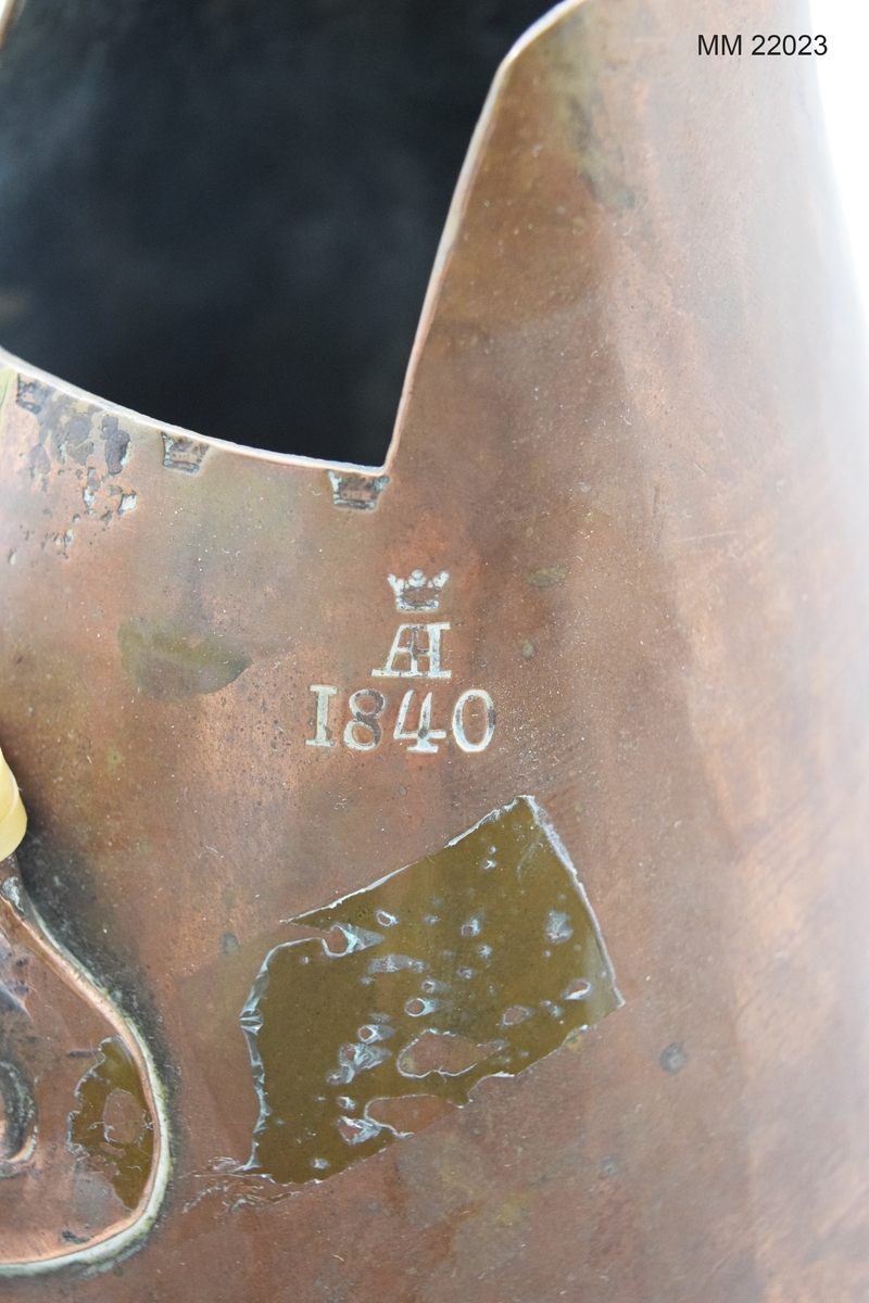 Brännvinsstop av koppar avsett för blommor. På handtaget präglad text: "A I Löfgren". Vid handtaget stansade fem kronor på rad samt krona och därjämte "AH 1840".
X 26