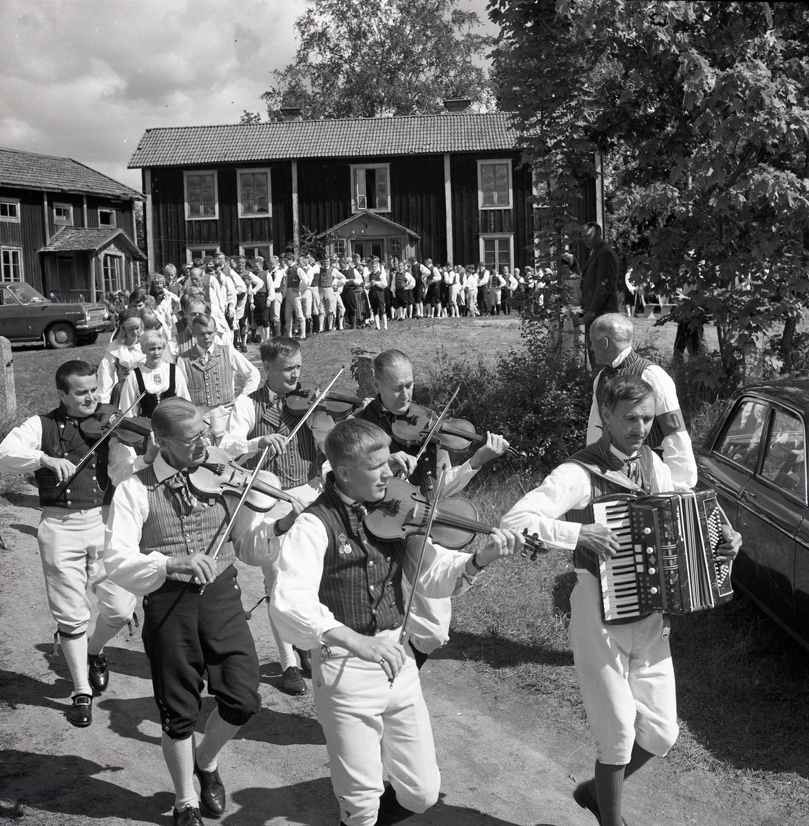 Spelmän iklädda hembygdsdräkt tågar från hembygdsgård under Hårgadansen,13 juli 1968.