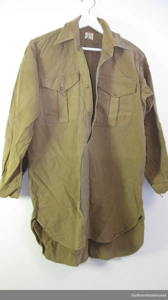 Skjorte  - militær skjorte. Lange ermer , to brystlommer. Nederste delen av skjorta er  sydd sammen. Skjorta er sidere bak enn foran.  Skulderklaffene er skåret av.