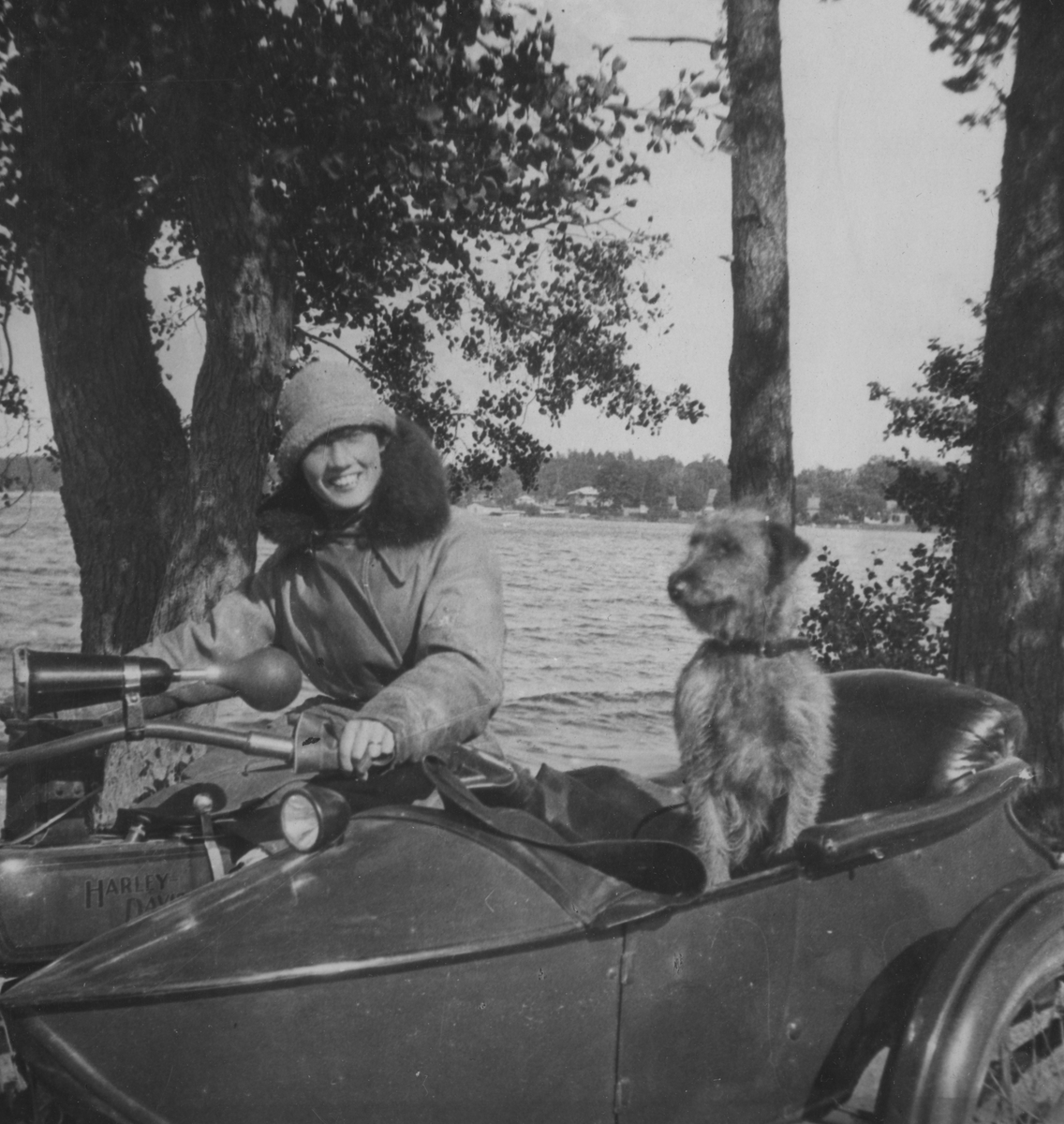 Anna Linderstam och en hund på en motorcykel med sidovagn vid en sjö, 1925.

Text vid foto: "Två käcka motortöser: AL, BK."