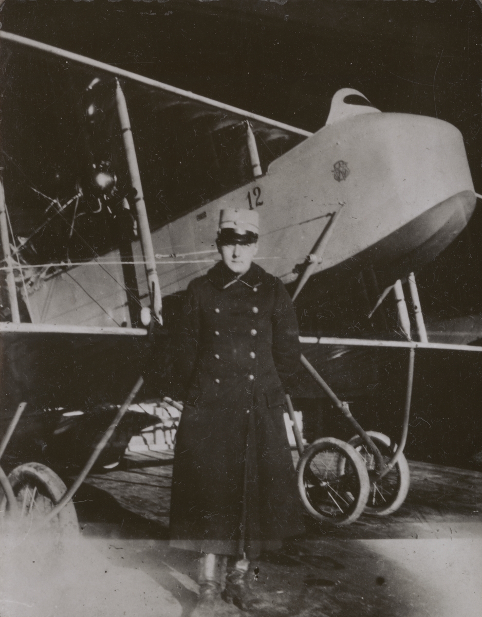 Militäre flygföraren Nils Kindberg står bredvid flygplan SW 10 Farman nr 12 i en hangar på Flygkompaniet på Malmen, 1915.