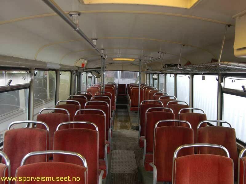 Rød buss med hvite striper med to inngangs- og utgangspartier. Interiøret består av røde seter, lyst tak og "hyller" med plass til bagasje over setene på venstre side. 