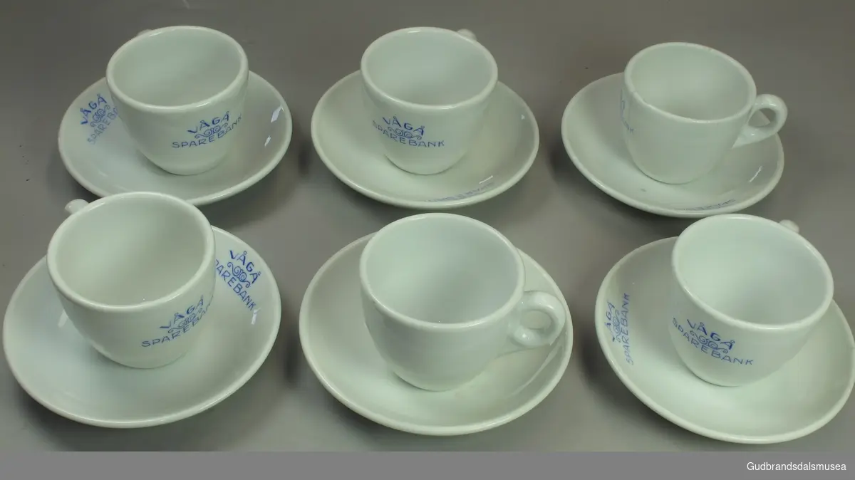 Seks kaffekopper med skål. Blå påskrift. To kopper har en sprekk.
