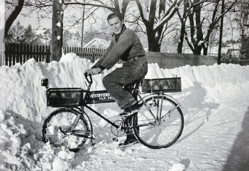Svart-hvitt foto av ung mann på viserguttsykkel i snøen.