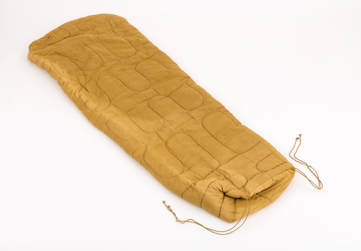 Vattert sovepose med bomullstrekk. Soveposen har en gul-grønn farge. Det er en beige glidelåsåpning i soveposen øvre del. Hodeåpningen er rund i formen, og det er en tynn kant som omslutter hodeåpningen. Hodeåpningen har en omkrets på 13 cm. 
Det festet to snorer på begge ytterkantene av fotenden. Disse snorene er til å knyte sammen den sammenrullede posen for frakt og oppbevaring.

Det er en løs lapp tilhørende soveposen "Medsend vennligst denne kontrollseddel ved eventuell reklamasjon. På baksiden står det Syerske:, Kontroll: . Denne lappen tyder på at gjenstanden er norskprodusert.