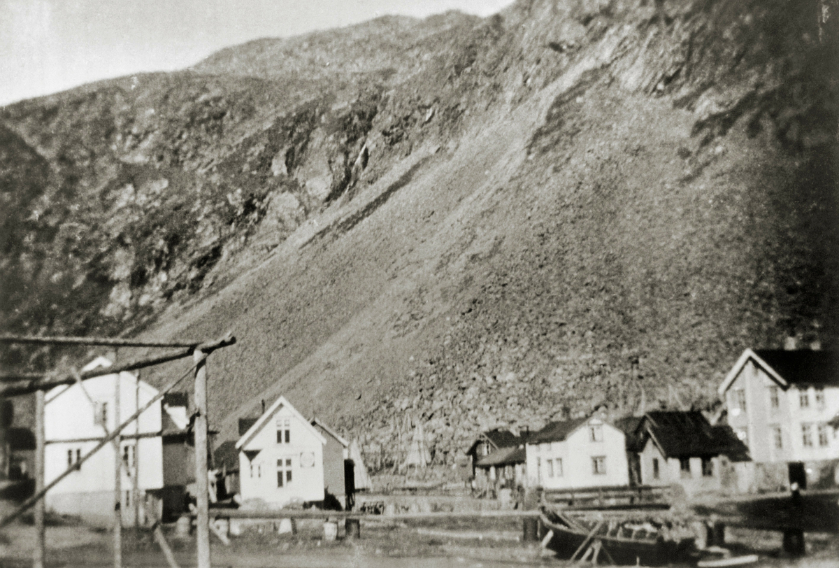 Bildet viser et parti av Finnkongkeila fra 1920. Fotografert fra fjæra (eller fra båt på havna): noen båter er trukket opp på land, vi ser bygninger og fjellsida i bakgrunnen.