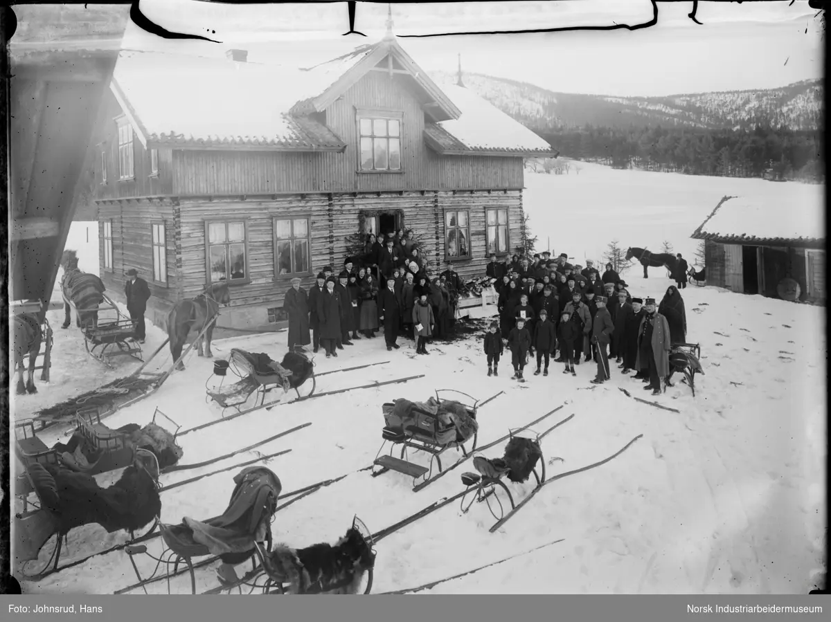 Gruppe foran et hus i gårdstun. Hester og sleder i forgrunnen. Fra begravelse av Ingebret Søvde som døde 23.01.1924.