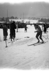 En skiløper med startnummer åtte i full fart i løypa. Mange 