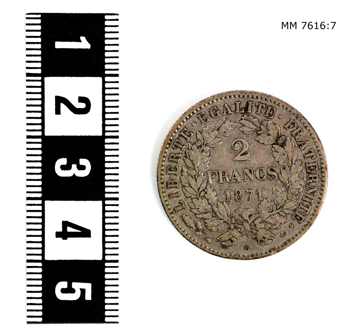 Mynt av silver. 2 francs Frankrike. Präglad på ena sidan: "Republique Francaise" samt figur med krans, på andra sidan: "2 francs 1871 Liberte Egalite Fraternite".