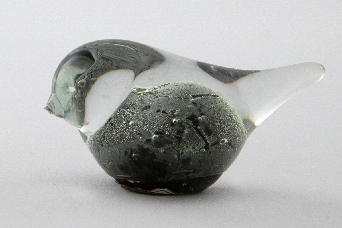 Glassfigur i klart og sortfarget opakt glass. Stilisert fugleform samt luftbobler.