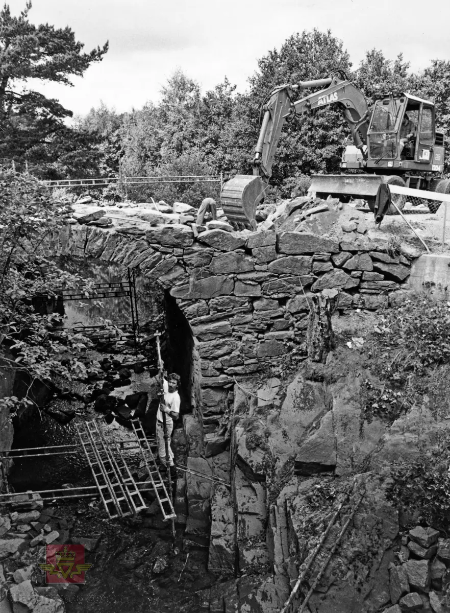 Helvedesbrua  ved gamle Tingsaker bru i Lillesand. Atlas gravemaskin i aksjon på steinhvelvbrua.
Stedsnavn: Tingsaker