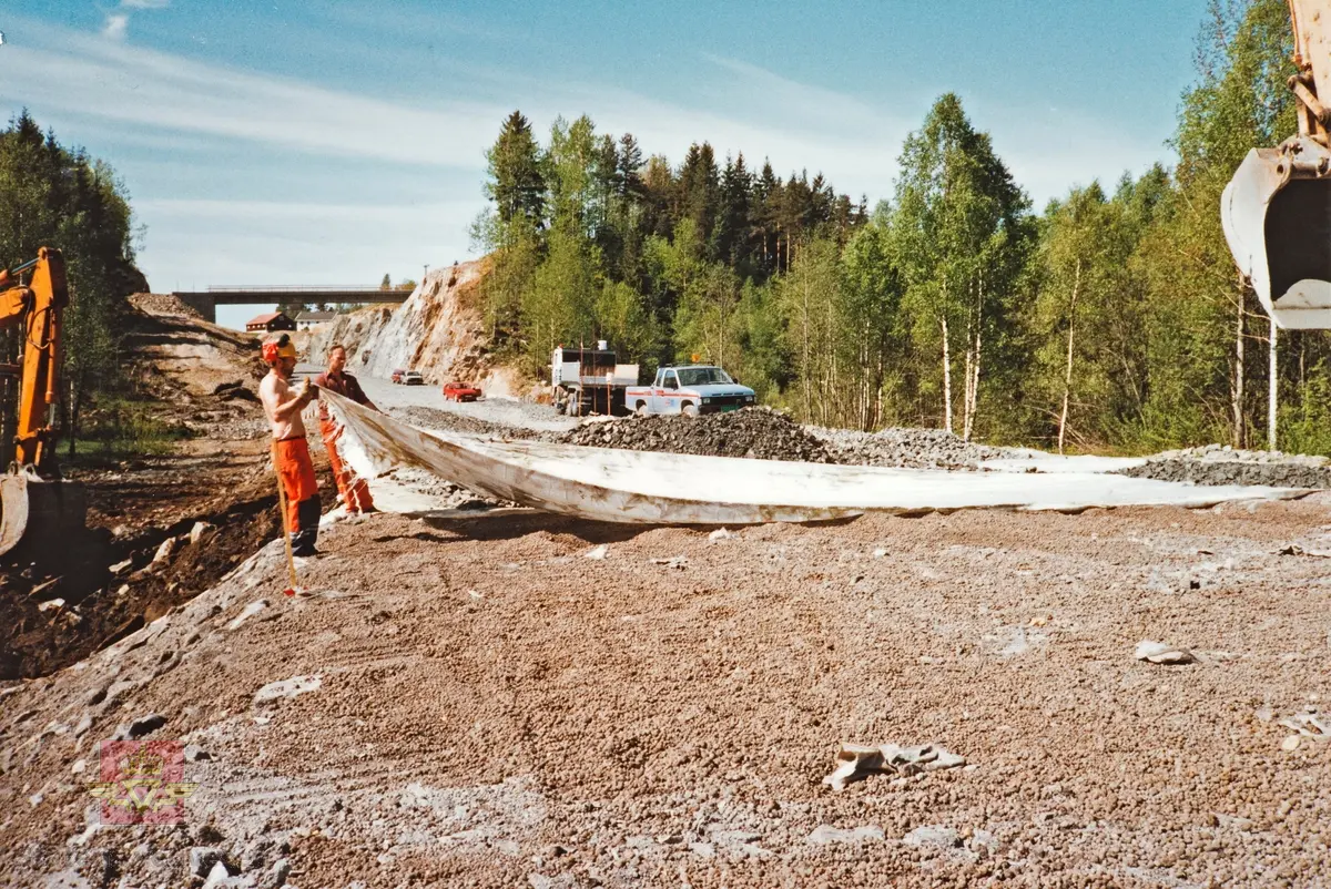 E18-anlegget Østerholtheia-Brokeland ved E18 i Gjerstad.
Fiberduk/filterduk til bærelag legges på. 
Fra venstre: Bjørn Urfjell, Salve Felle. 
Stedsnavn: Sundsmyra
