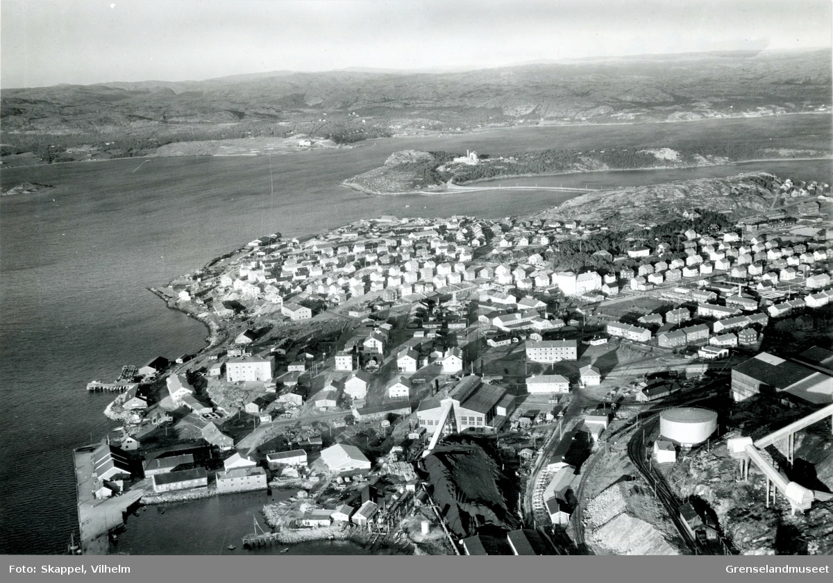 Flyfoto av Kirkenes med Jakobsnes og Ytre Lid i bakgrunnen. Sabelskjær til venstre i bildet. Prestøya fra midten og mot høyre i bildet. Kulturhuset Malmklang. Deler av AS Sydvaranger i høyre front av bildet.