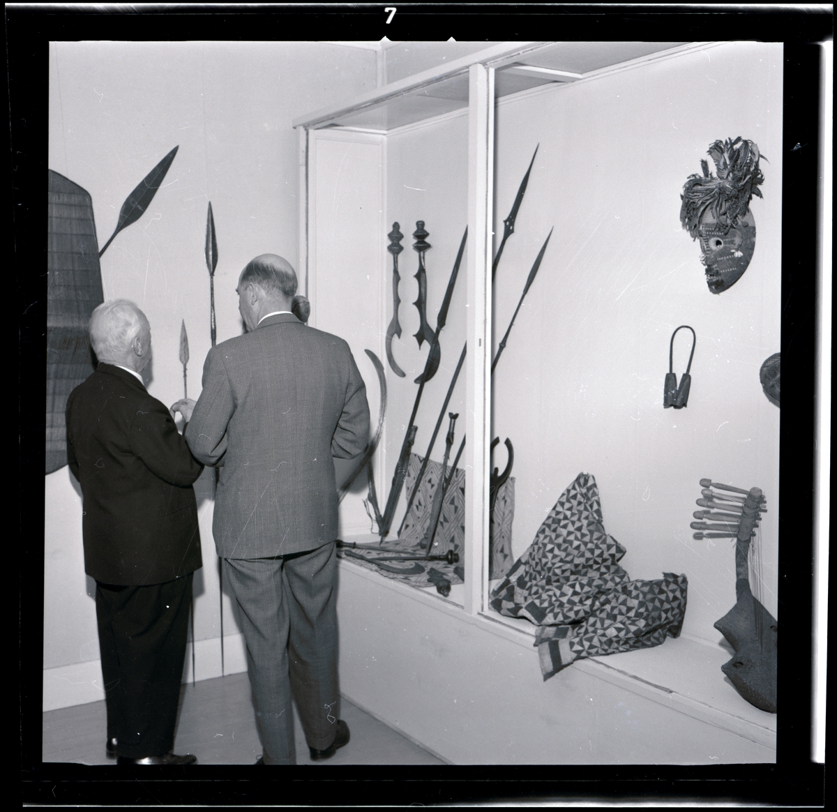 Text till webbutställning "Från när och fjärran" presenterad på Bohusläns museums hemsida år 2009:
Svärd, järnsmide med ciselerade ornament, handtaget av trä prytt med geometriskt mönster av mässingsnitar, längd 67,5 cm.
Gåva av sjökapten Elmer Göransson år 1961. 

Uppgifter om givaren
Under sin 30-åriga vistelse i Belgiska Kongo skötte Elmer Göransson (1872-1964) under många år transporter på landets floder. När han år 1932 avslutade sin tjänstgöring var han både skeppsfartygsinspektör för hela den belgiska flottan i övre Kongo, t. f. chef för hydrografiska tjänsten samt hamnkapten i Leopoldville.
Han var samlare av bl.a. vapen, textilier och träkärl. I omgångar från 1919 skänkte Göransson afrikanska föremål till Uddevalla museum. Han kom att bli en av museiföreningens hedersledamöter.
Vid sin bortgång 1964 var han bosatt i Kungsbacka.

Artikel i Bohusläningen från måndagen den 1 november 1937.
"Vittberesta bohusläningar berätta. Upplevelser under 30-årig vistelse i Belgiska Kongo. Kapten Elmer Göransson. Folk och sedvänjor under ekvatorns glödande sol."
_______________________________________________________________________

Kontinent: Afrika
Eneggad klinga, kraftigt svängd och på ryggen försedd med utskott; bladet rikt mönstrat med graverad dekor. Fästet virat med järnband; träskaftet består av två vulster och som avslutning en knoppform, trädelen prydd med kupolformade mässingsnubb. 
Bangala (möjl. Bobangi).

Litteratur:
"Naturfolkens Lif", populär etnografi skriven av W. Dreyer, översätt av D:r J. F. Nyström, Expeditionen af Ljus, Stockholm 1899.
Fig. 154 Afrikansk masugn till järnmalmens utsmältning
Fig. 156 Afrikanska smeder
Fig. 170 Krigskanot på Kongofloden
Fig. 171. Afrättning i en negerby vid Kongofloden.

W. Dreyer skriver i den svenska översättingen av boken "Naturfolkens Lif," från 1899: Men framför alla andra handtverk är smideskonsten utvecklad, och smederna bilda en klass, ja, nästan en kast för sig; deras barn få lära sig yrket från det de äro små. Nästan öfverallt finnes järnmalm i jorden och negrerna utsmälta själfva järnet ur den. De uppföra en smältugn af lera, i regeln blott liten och enkel, ibland dock ett par meter eller mera hög och fullkomligare inredd. Den fylles med omväxlande lager af träkol och malm; elden tändes nedtill och då man sörjt för drag försiggår förbränningen raskt. Det utsmälta järnet samlas i en fördjupning på botten och uttages till vidare bearbetning.
Smedens redskap äro få och enkla: en större sten till städ, en mindre till hammare, som föres i handen, en dubbel blåsbälg af getskinn, hvilken sen medhjälpare håller i gång genom att omväxlande sammantrycka och utvidga hvar avdelning för sig; det är allt.
Med dessa tarfliga redskap förstår han dock att smida härliga vapen, spjut, yxor o.s.v., hackor till jordbruket, ringar till smycken, bjällror och mycket annat. Metallens godhet är förvånande, den kan täfla med det bästa engelska järn, och tekniken är förbluffande. Vackert ciselerade sirater, inläggningar med koppar, genombrutna arbeten o.s.v. förstå dessa handtverkare, nästan konstnärer i sitt fack, att åstadkomma.

Uppgifter om E. Göransson i Knut Adrian Anderssons katalog samt historik om samlingen: Se UM61.03.001.