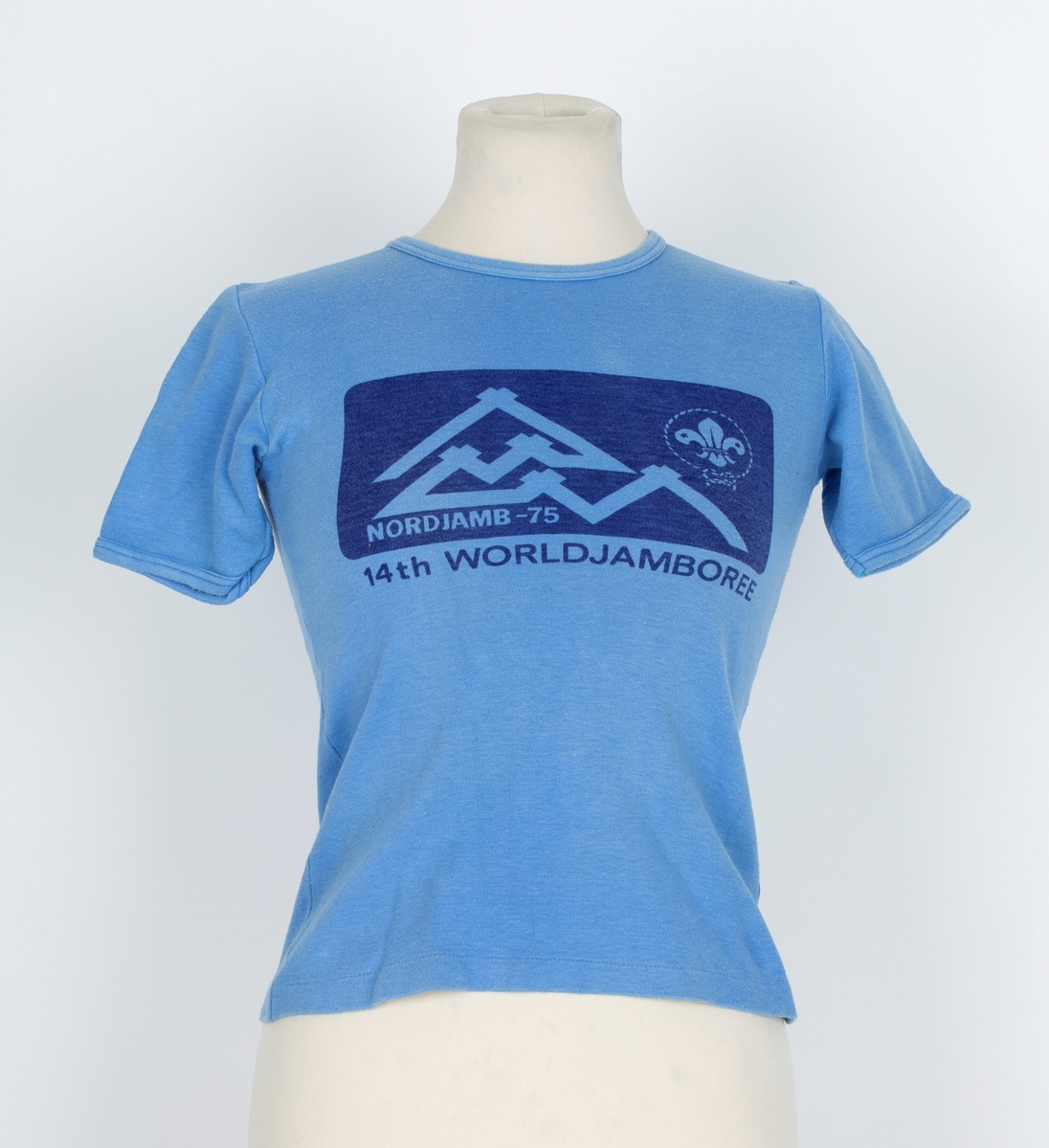 T-skjorte. Blå. påtrykt mørk blått felt på brystet, telt, speiderlilje, Norjamb 1975. 14. world jambore
Antatt brukt av sønne Jørn f. 1960