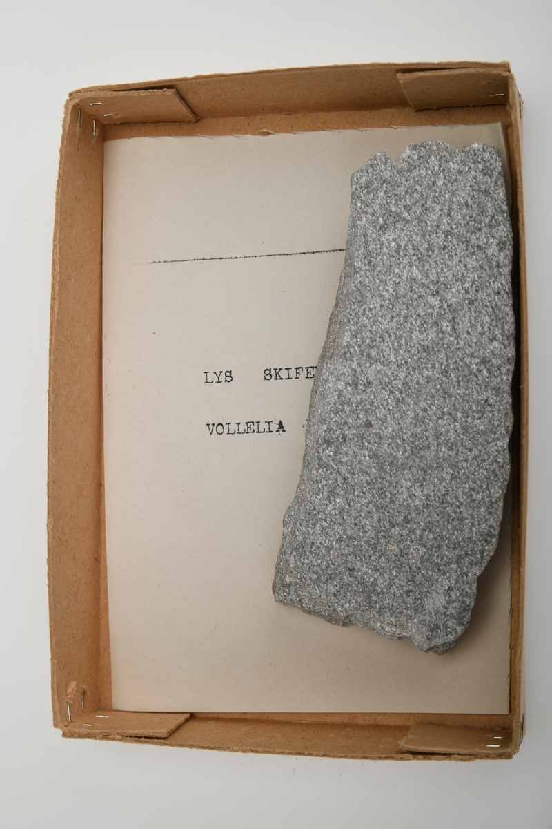 Et stykke lys skifer som er lys grå på farge (med sølvskimmer). Steinen er fra Vollelia i Oppdal, Trøndelag.
Del av steinsamlingen som inngår i skolesamlingen.