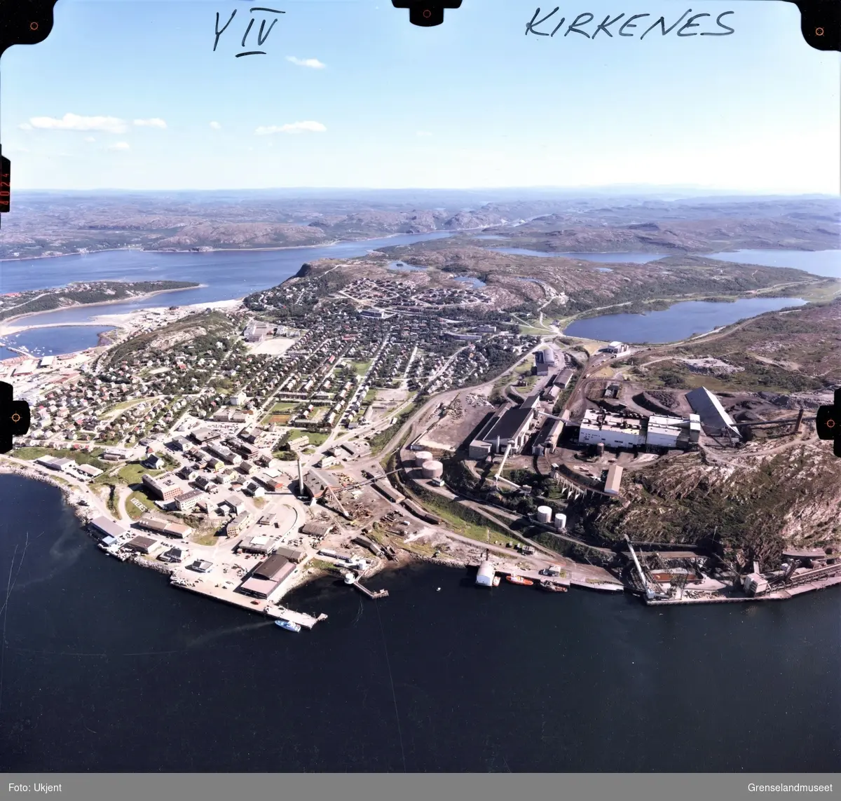 Flyfoto av Kirkeneshalvøya med utsikt mot Elvenes. AS Sydvaranger sitt industriområde til høyre i nedre del av bildet med Førstevann rett bak. Prestøya med sykehuset til venstre. Kirkenes Barne- og Ungdomsskole med fotballbanen, mot venstre. 