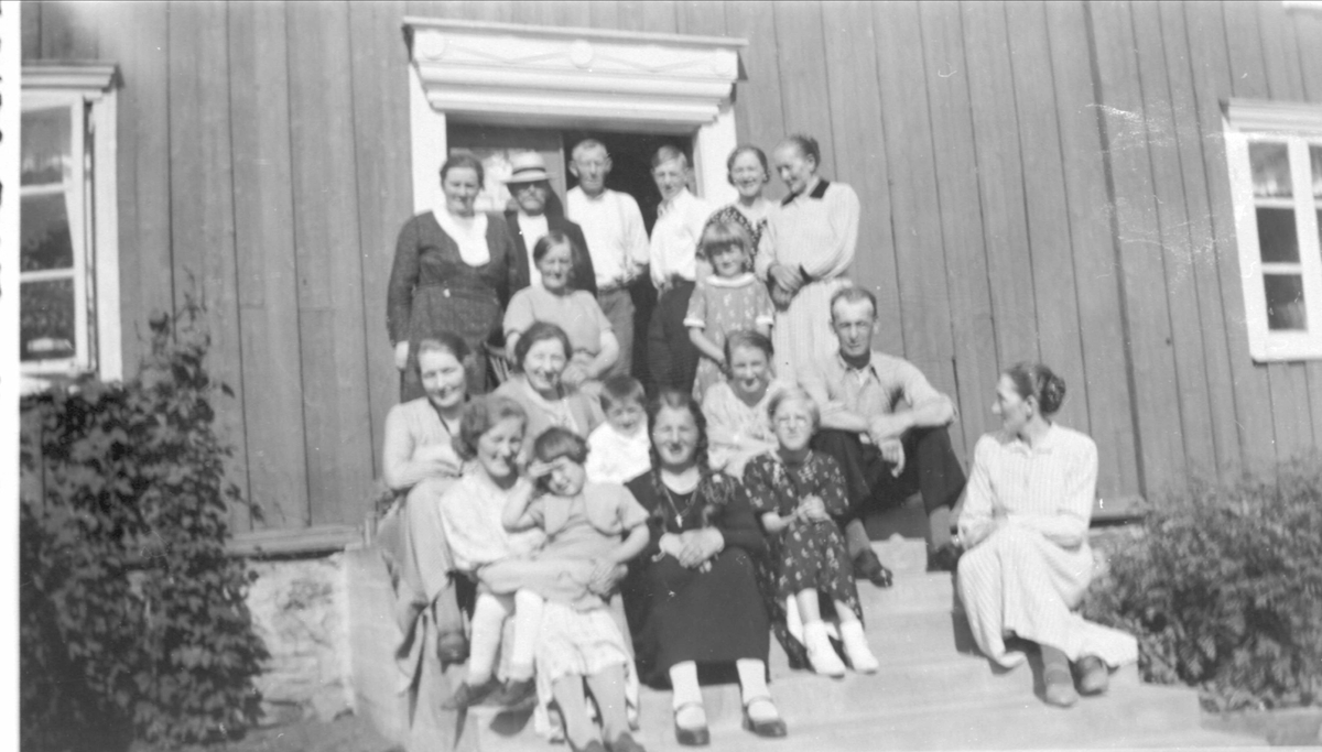 Gruppebilde av familien Rasmussen med flere, på trappa foran bolighus.