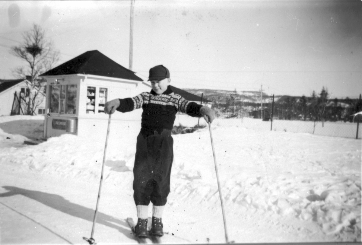 Gutt på ski stående foran en liten kiosk på Evenskjer.