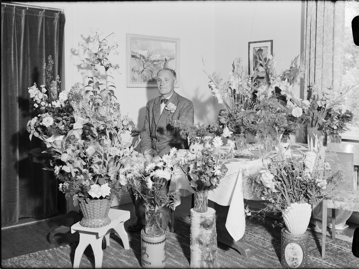 Man i hemmiljö omgiven av blommor, Uppland 1950
