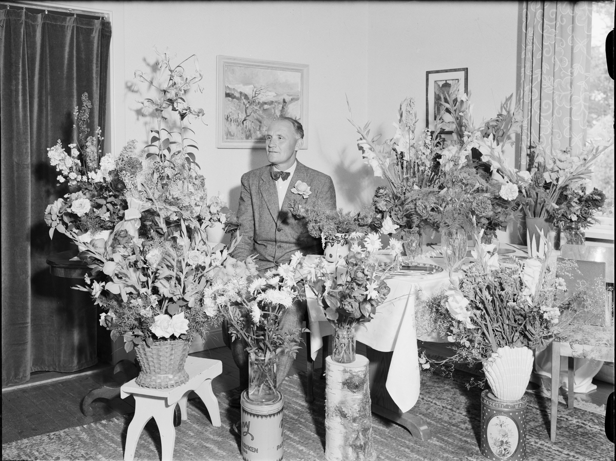Man i hemmiljö omgiven av blommor, Uppland 1950