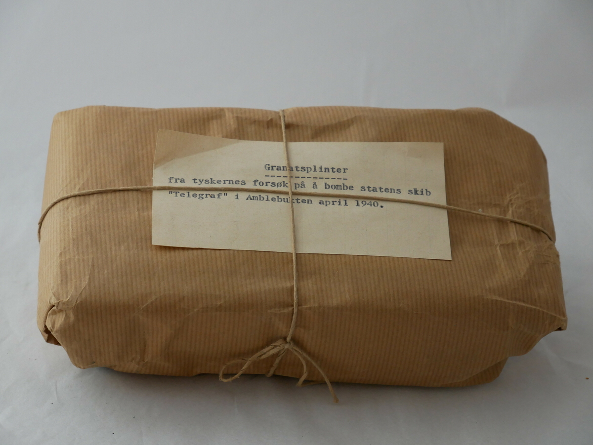 Ein pakke med granatsplinter merka med notatet: "Granatsplinter fra tyskernes forsøk på å bombe statens skib "Telegraf" i Amblebukten april 1940