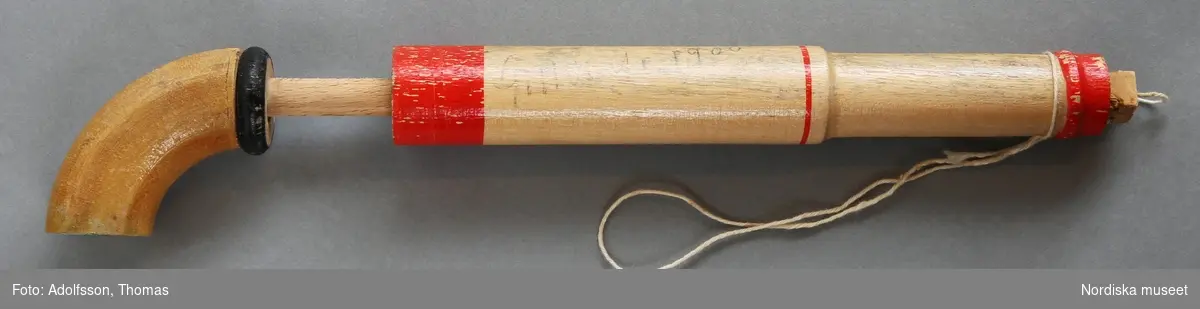 Inventering Sesam 1996-1999:
L 24   Diam 2,5 (cm)
Pistol, korkpistol, leksak, svarvat ihåligt trärör med lätt böjd skjutkolv, som genom tryck skall avlossa 4-kantig korkbit, fäst med snöre (snöret av).
Trol. upptagen som "No 31 i Waru matrikel för Nya Leksaksfabriken Gemla 1900" (handskriven), hittad i lagerbyggnad, som revs hösten 1973, av dir. Henriksson, som var knuten till fabriken från 1908 till nedläggelsen omkr. 1950.
Mars 1974 TC [=Teje Colling]