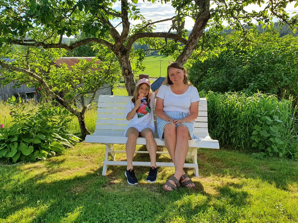 To jenter sitter under epletreet på Åpent bygdetun