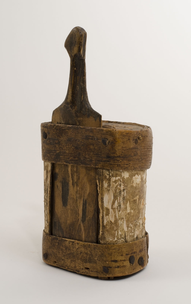 Ask, näverask av trä, utvändigt klädd med näver, i form av en längs ena sidan något avskuren cylinder. Försedd med skjutlock av trä med handtag.