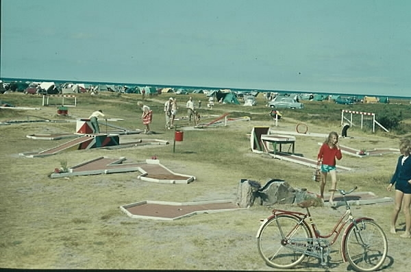 Några som spelar minigolf på Björkängs camping i Tvååker. Tälten syns i bakgrunden vid havet och i förgrunden står en damcykel.