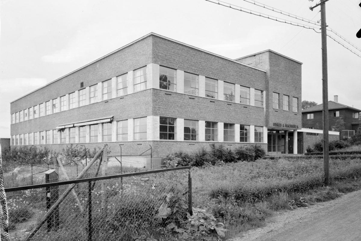 Arkitekturfoto av industribygg tegnet av far og sønn Thorvald og Henning Astrup. Over døra står "Udnæs & Isachsen A/S"