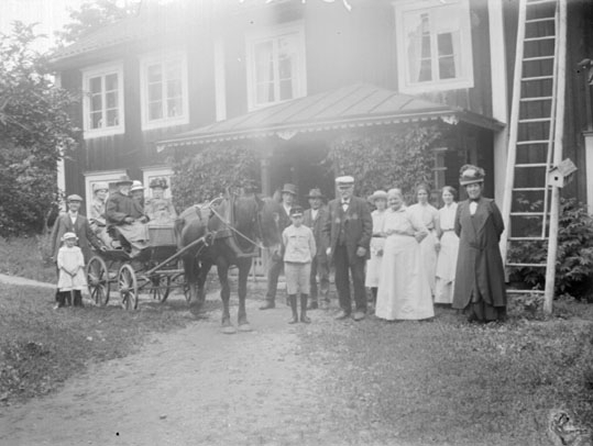 Grupporträtt, med häst och vagn framför gårdens veranda.