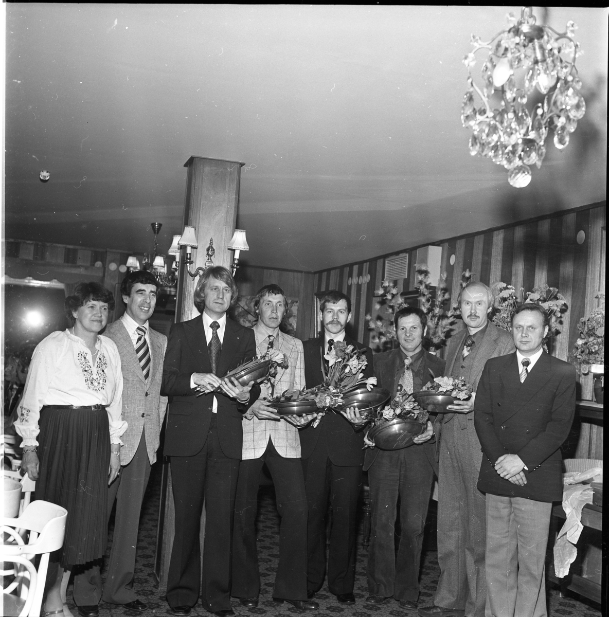 Gruppbild med åtta män och kvinnor varav flertalet håller tennfat och blommor i famnen. Till vänster står Karin Wenner och Tom Sonesson. Till höger står Allan Svensson.