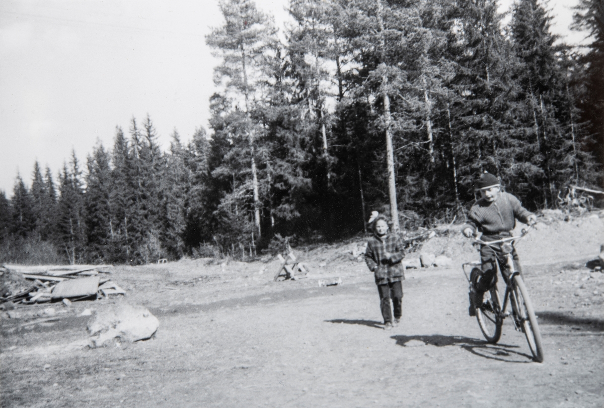 Einar Behrns har akkurat lært å sykkel, mens Oddveig Storlien (f: Krokengen) ser på. Her oppe ved Moelven Kraftstasjon