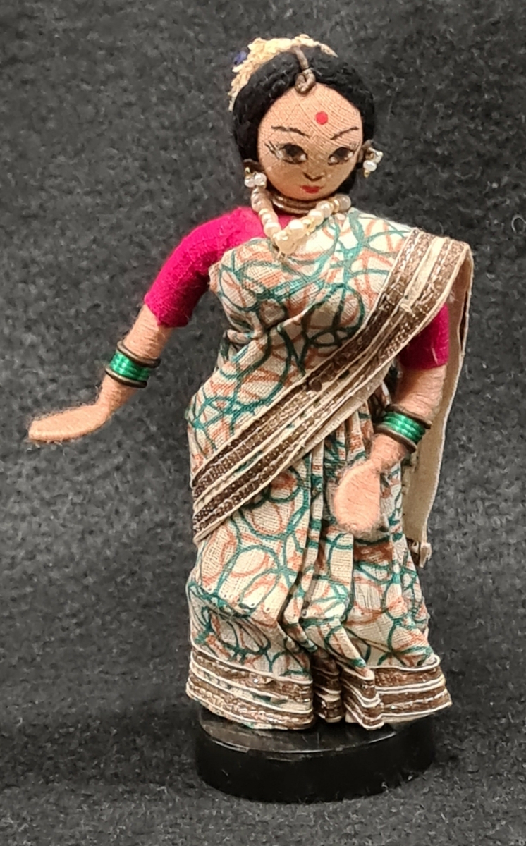 Docka som tillhör Vera Hanssons docksamling.

Köpt 1976. Vijaya, Indien. Grönmönstrad sari och röd blus. Pärlhalsband.