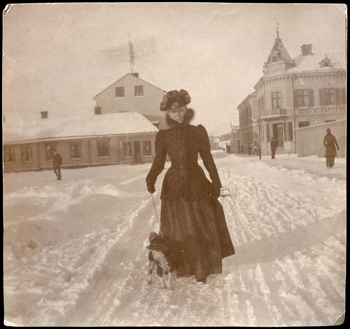 Vintermotiv kvinna med hund, Torggatan vid Stora torget, Enköping, vy från sydöst, ca 1898-1902.